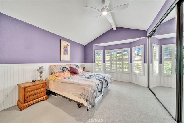 carpeted bedroom featuring multiple windows, lofted ceiling with beams, a closet, and ceiling fan