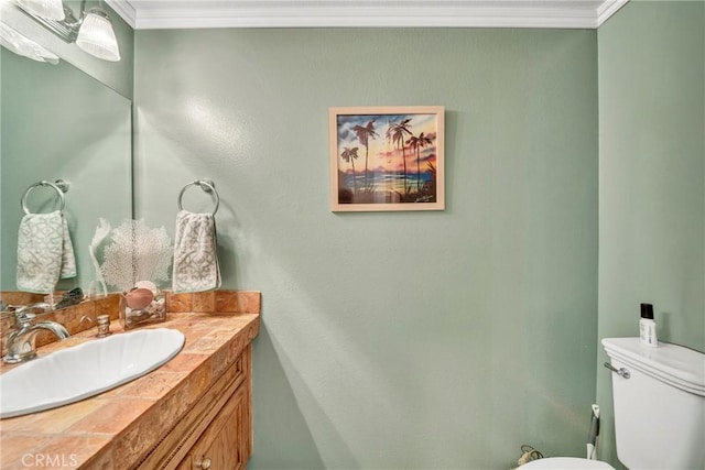 bathroom with toilet, vanity, and ornamental molding