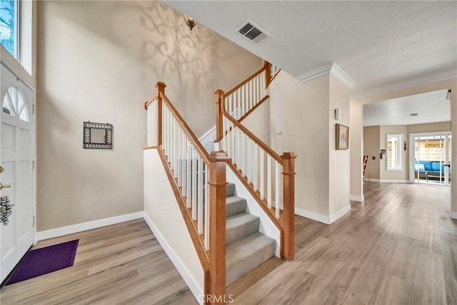 staircase featuring ornamental molding, hardwood / wood-style flooring, and a healthy amount of sunlight