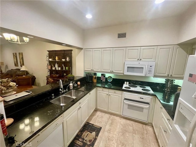 kitchen featuring white appliances, dark stone counters, sink, white cabinetry, and kitchen peninsula