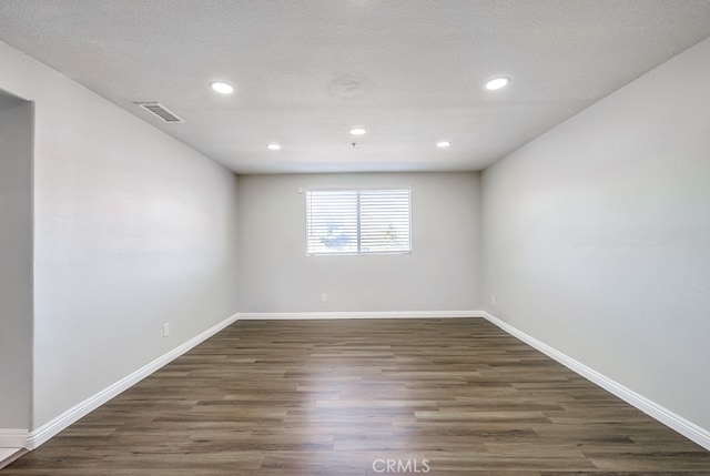 unfurnished room with a textured ceiling and dark hardwood / wood-style floors