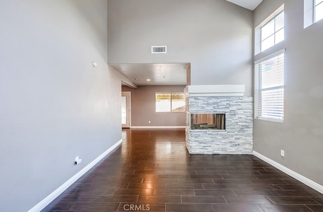 unfurnished living room with a towering ceiling, a fireplace, and plenty of natural light