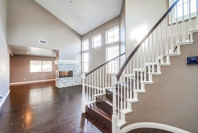 staircase featuring a high ceiling, hardwood / wood-style floors, and a fireplace