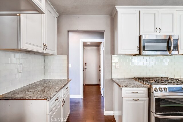 kitchen with light stone countertops, white cabinets, dark wood-type flooring, and appliances with stainless steel finishes