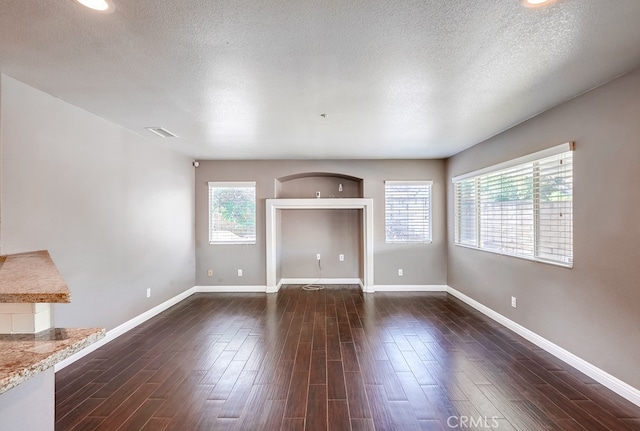 unfurnished living room featuring dark wood-type flooring and a textured ceiling