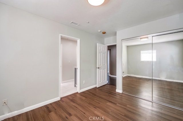 unfurnished bedroom with a closet and dark hardwood / wood-style floors