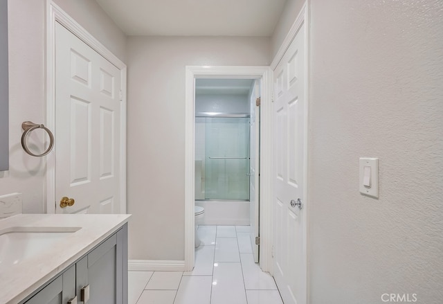 full bathroom featuring shower / bath combination with glass door, tile patterned flooring, toilet, and vanity