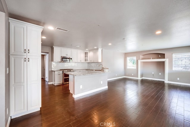 kitchen featuring white cabinets, light stone counters, tasteful backsplash, dark hardwood / wood-style flooring, and appliances with stainless steel finishes