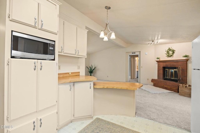 kitchen with white cabinetry, light colored carpet, pendant lighting, and a brick fireplace