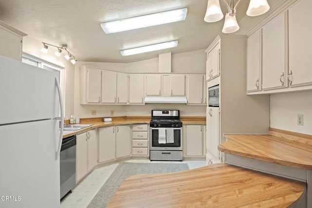 kitchen with a textured ceiling, stainless steel appliances, white cabinets, hanging light fixtures, and lofted ceiling