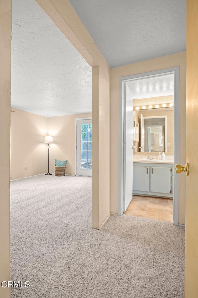 hall featuring light carpet and a textured ceiling