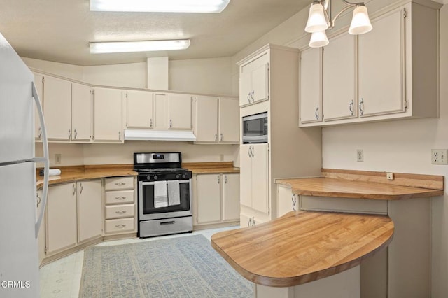 kitchen with kitchen peninsula, appliances with stainless steel finishes, decorative light fixtures, and white cabinetry