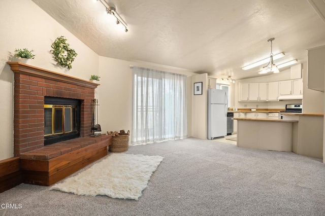 carpeted living room featuring a fireplace, track lighting, and lofted ceiling