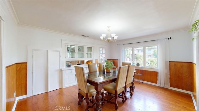 2049 Argyle Ave, Los Angeles, CA 90068 - dining space featuring a chandelier, wainscoting, light wood finished floors, ornamental molding, and wood walls