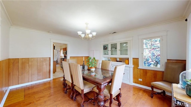 2049 Argyle Ave, Los Angeles, CA 90068 - dining area featuring a wainscoted wall, a chandelier, light wood finished floors, wood walls, and crown molding