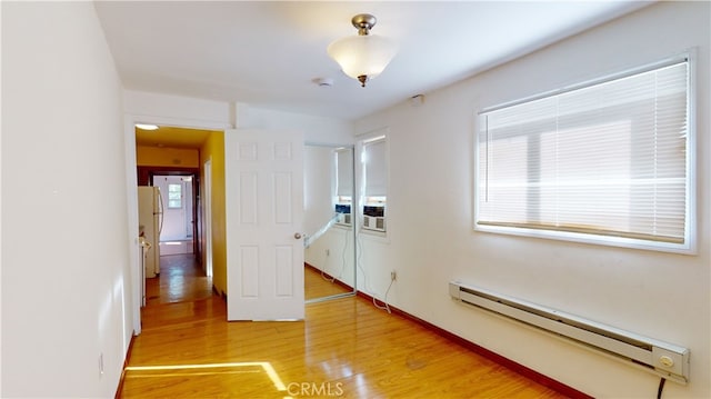 unfurnished room with hardwood / wood-style floors and a baseboard radiator