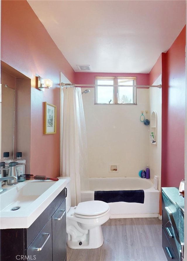 full bathroom with shower / bathtub combination with curtain, hardwood / wood-style floors, vanity, and toilet