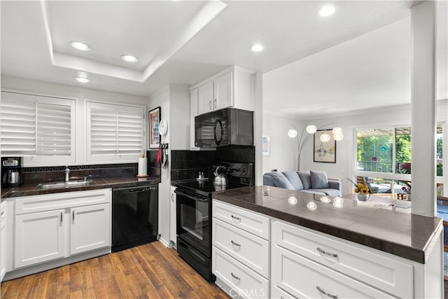 kitchen with black appliances, white cabinets, kitchen peninsula, and sink