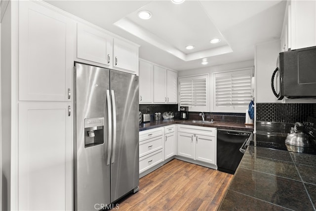 kitchen featuring hardwood / wood-style floors, a raised ceiling, stainless steel refrigerator with ice dispenser, black dishwasher, and white cabinets