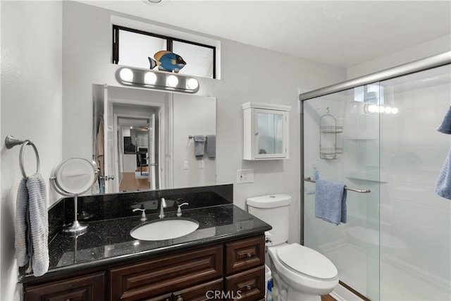 bathroom featuring an enclosed shower, vanity, and toilet