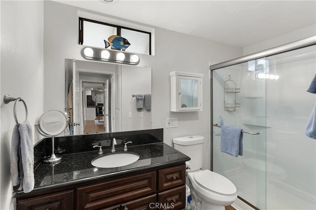 bathroom featuring toilet, a shower with door, and vanity