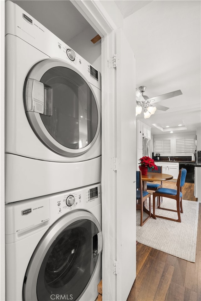 clothes washing area featuring ceiling fan, dark hardwood / wood-style flooring, and stacked washer / dryer