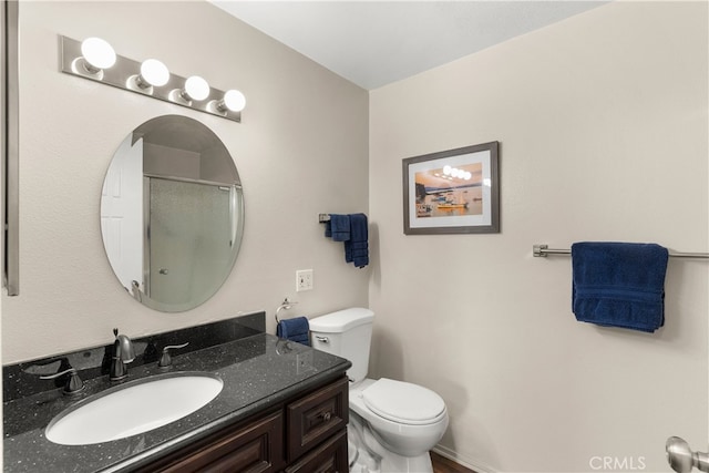 bathroom featuring a shower with door, toilet, and vanity