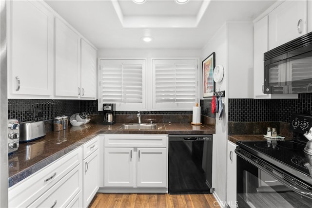 kitchen with backsplash, black appliances, sink, light hardwood / wood-style flooring, and white cabinets