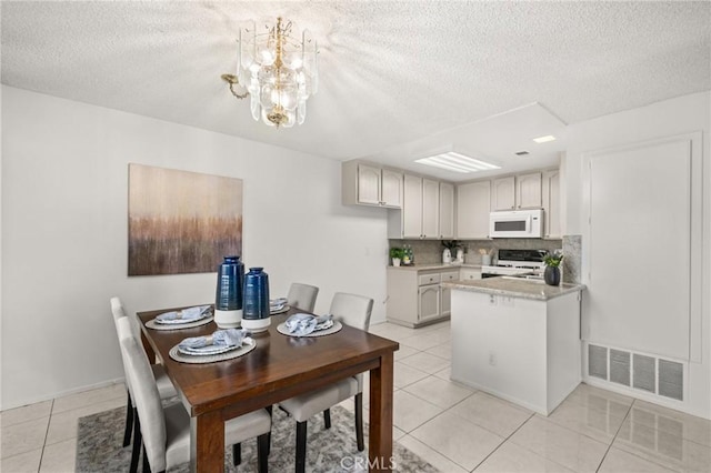 tiled dining space with a chandelier and a textured ceiling