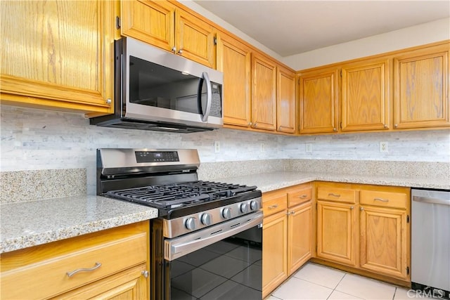 kitchen with decorative backsplash, light stone counters, light tile patterned floors, and appliances with stainless steel finishes