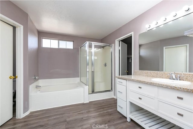 bathroom with hardwood / wood-style floors, vanity, and plus walk in shower