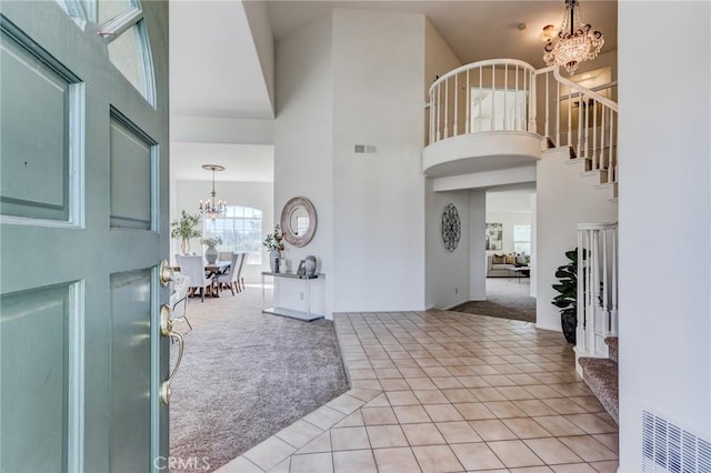 entryway with light colored carpet, a towering ceiling, and a chandelier