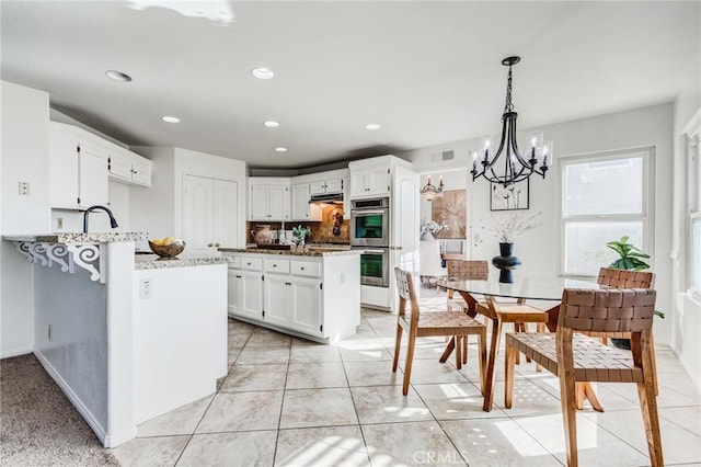 kitchen featuring light stone counters, decorative light fixtures, recessed lighting, double oven, and white cabinets