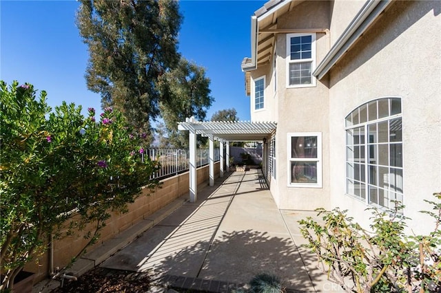 view of side of property with a fenced backyard, a patio, a pergola, and stucco siding