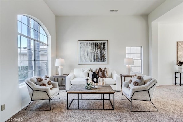 carpeted living area featuring baseboards and visible vents