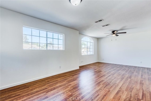 empty room featuring light wood-type flooring, visible vents, and baseboards