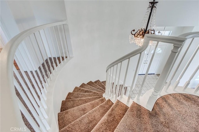 stairway featuring a towering ceiling and an inviting chandelier