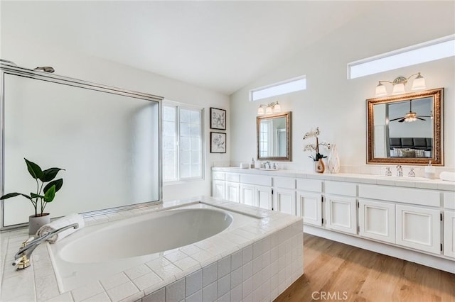 full bath featuring ensuite bathroom, wood finished floors, a sink, vaulted ceiling, and double vanity