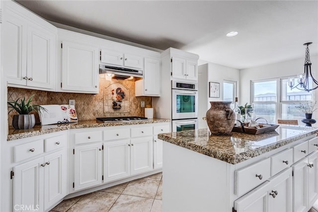 kitchen featuring under cabinet range hood, white cabinetry, appliances with stainless steel finishes, and a center island