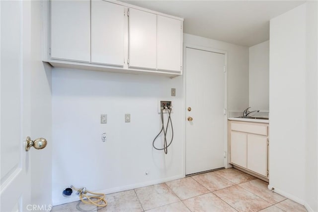 clothes washing area featuring light tile patterned floors, washer hookup, a sink, baseboards, and cabinet space