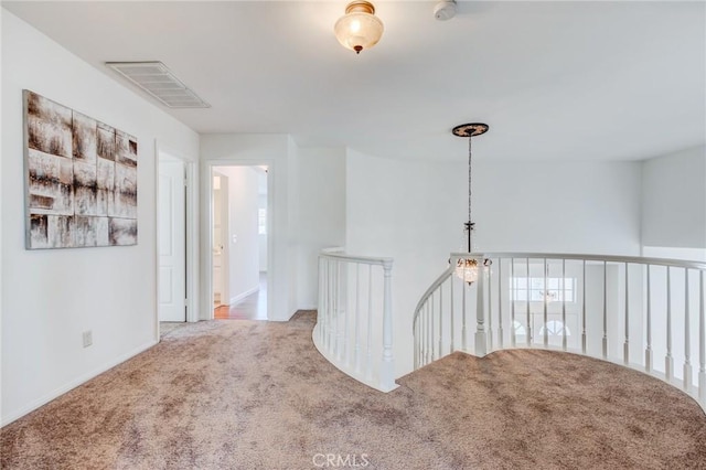 hallway with an upstairs landing, carpet flooring, and visible vents