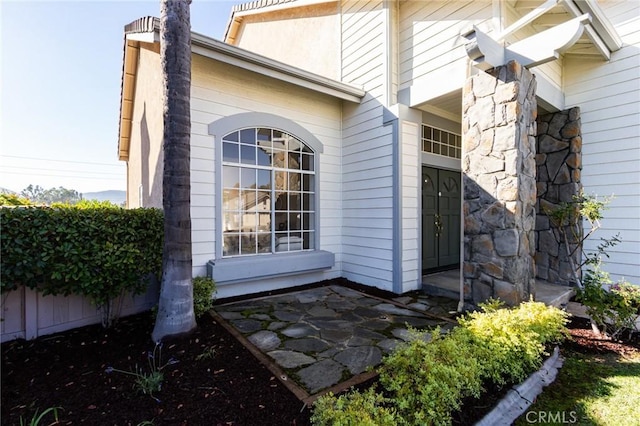 view of property exterior featuring stone siding and fence