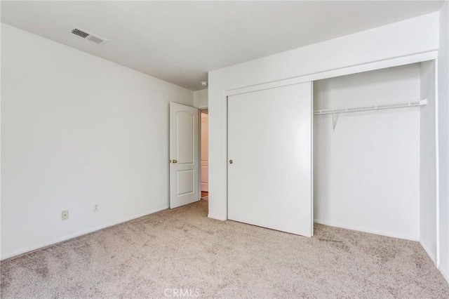 unfurnished bedroom featuring light colored carpet, a closet, and visible vents