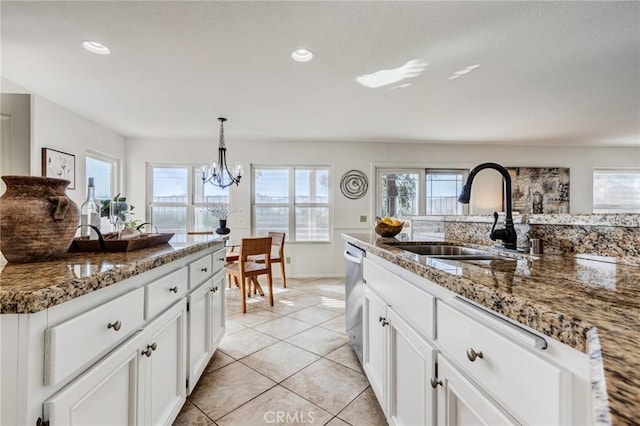 kitchen featuring light tile patterned floors, white cabinets, dark stone countertops, pendant lighting, and a sink