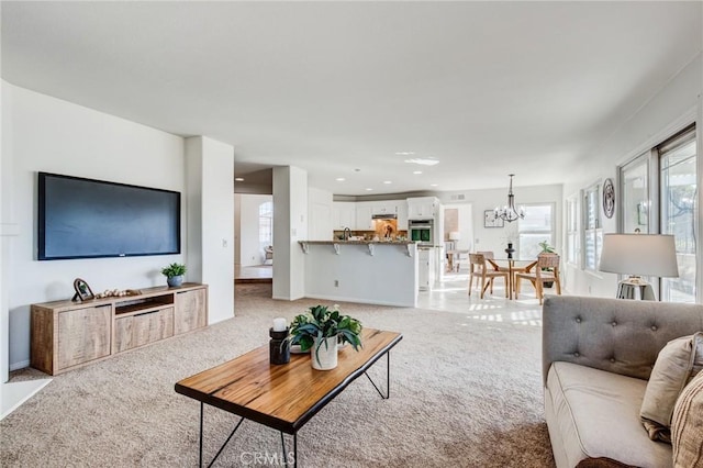 living area featuring light carpet, baseboards, a chandelier, and recessed lighting