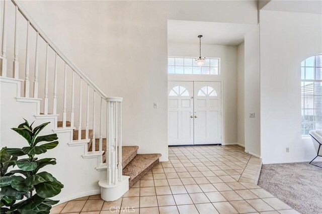 foyer entrance featuring light carpet and a high ceiling