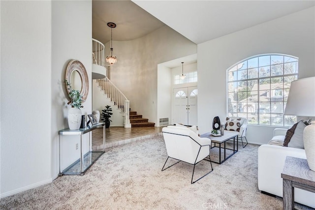 living room featuring light carpet, a high ceiling, visible vents, baseboards, and stairway