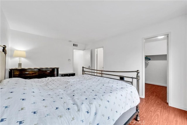 bedroom with a closet, a spacious closet, and hardwood / wood-style floors