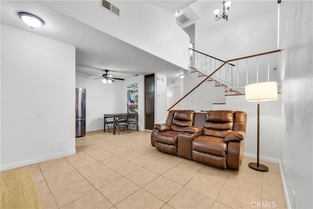 tiled living room with ceiling fan with notable chandelier