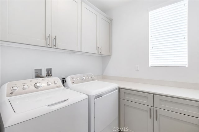 laundry room featuring washer and clothes dryer and cabinets